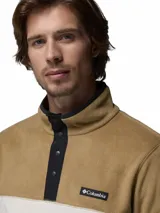 Buzo polar Columbia modelo Steens Mountain, de diseño color block en tonos beige y blanco. Presenta cuello alto con cierre de botones a presión, mangas largas y logo de la marca bordado en el pecho.