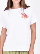 Remera blanca de manga corta con cuello redondo y un estampado frontal de un jarrón azul a rayas con flores rosadas.