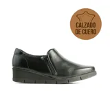 Zapato casual de cuero negro con diseño de taco corrido y cierre lateral. Presenta una textura granulada y suela de goma flexible.