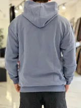 Canguro oversize de color azul, con capucha, bolsillo frontal tipo canguro y diseño bordado en el pecho. Cuenta con puños y cintura elastizados.