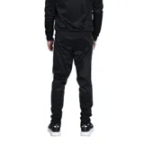 Conjunto deportivo Umbro compuesto por campera con cierre frontal y pantalón de jogging, ambos en color negro con detalles de bandas laterales y cierres en blanco. La campera presenta cuello alto y bolsillos laterales, mientras que el pantalón cuenta con ajuste elástico en la cintura y tobillos.