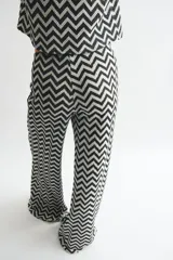 Pantalón de tiro alto confeccionado en punto jacquard con diseño de zigzag en blanco y negro. Presenta un corte de pierna amplia y cintura elástica.