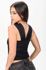 Top negro con escote off-shoulder, diseño cruzado con frunces en el frente y detalle de anilla metálica central.