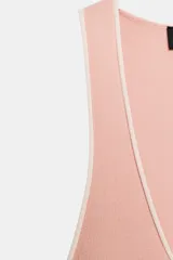 Top de punto color rosa pálido, de corte ajustado, con escote redondo y tirantes anchos. Presenta un ribete de color blanco contrastante en el escote y las sisas.
