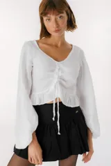 Falda corta tipo balloon color blanco, con cintura alta y diseño con volumen. Presenta una pequeña placa metálica con el logo de la marca en la parte frontal.