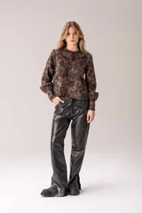 Camisa de manga larga marrón con estampado floral en negro, cuello mao con volados, pliegues frontales y puños ajustados.