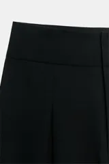 Pantalón balloon de tiro alto color negro con pliegues en el delantero y bolsillos laterales ocultos en la costura.