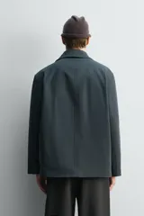 Chaquetón de corte relajado confeccionado en tejido técnico con mezcla de algodón. Presenta cuello solapa, cierre frontal con cremallera oculta por solapa con botones a presión, bolsillos de plastrón con solapa en la cadera y forro interior a contraste.