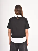 Remera de manga corta con diseño de doble capa, combinando una remera negra lisa con un cuello y ruedo de camisa blanca por debajo.