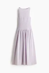 Vestido midi sin mangas confeccionado en sirsaca de algodón color lila, con cuerpo ajustado de punto smock, escote redondo y falda amplia con vuelo y costura fruncida en la cadera.