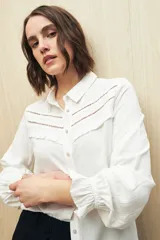 Camisa verde clara de manga larga confeccionada en viscosa ligera, con cuello clásico, cierre frontal con botones, detalles calados en la parte superior y pequeños volados.