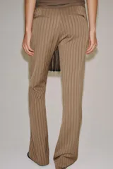 Pantalón flare de tiro medio, confeccionado en mezcla de viscosa y lino, con diseño de rayas verticales en tono beige. Cuenta con bolsillos delanteros y bajo acabado en línea evasé. Cierre frontal con cremallera, botón y ganchos metálicos.
