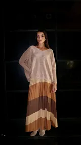 Pollera larga plisada con diseño de franjas horizontales en tonos marrón oscuro y beige brillante con lurex. Posee elástico en la cintura.