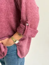 Sweater Ginebra de punto color magenta, con escote redondo, mangas largas con presilla y botón para ajustar, y diseño holgado con bajo asimétrico.