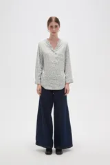Blusa de viscosa con estampado floral pequeño, cuello mao con escote en V y cierre frontal parcial de botones. Presenta mangas largas con puños y un bolsillo frontal en el pecho.