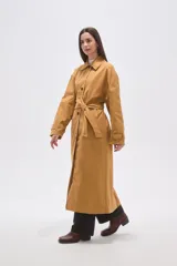 Trinchera larga de corte holgado, con cuello solapa, cierre frontal con botones y cinturón ajustable a la cintura. Cuenta con mangas largas y bolsillos laterales.