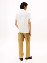 Chomba blanca de piqué de mezcla de algodón elástico, con tecnología Flex, que absorbe la humedad y es antiolor. Tiene cuello de chomba, billetera de dos botones, detalles distintivos de Tommy Hilfiger Sport y logo de Tommy Hilfiger Sport en el pecho.