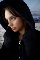 Chaqueta tipo teddy color negro, con capucha, cierre frontal metálico y puños tejidos.