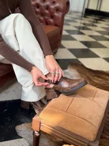 Zapato tipo zueco de cuero color chocolate con efecto desgastado, plataforma y taco cuadrado. Presenta una tira trasera ajustable con hebilla metálica.