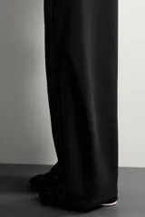 Pantalón de corte relajado confeccionado en tejido de algodón, con cintura elástica y detalle de pliegues estructurales en las perneras. Cuenta con bolsillos frontales y un bolsillo trasero de plastrón.