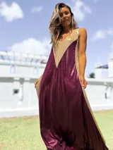 Vestido largo de corte holgado con diseño bicolor en tonos bordó y dorado, confeccionado en tela satinada con acabado brillante. Presenta escote en V y breteles anchos.