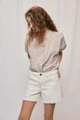 Short de jean blanco de tiro medio con silueta relajada y detalle de ruedo desflecado con flecos.