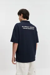 Remera polo color crema con logo bordado en el pecho, de corte amplio y mangas cortas.