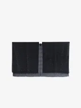 Capa tipo bufanda de tacto suave, con diseño en zigzag en tonos oscuros y detalles brillantes o lentejuelas. Presenta un escote en V cruzado y bordes deshilachados.