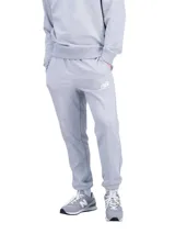 Pantalón deportivo New Balance modelo NBSSSWTPNT, color gris melange, con bolsillos laterales y puños elásticos en los tobillos. Cuenta con el logo bordado en la pierna izquierda.