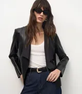 Campera de cuero sintético (PU) color negro, con diseño de solapas delanteras abiertas, mangas largas y corte recto. Presenta detalles de recortes a láser en la superficie.