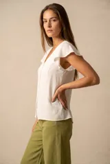 Blusa blanca con escote en V, mangas cortas con volados y cierre frontal con botones.