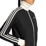 Campera deportiva Adidas con cierre frontal, cuello alto, mangas largas con las icónicas tres tiras blancas y puños y ruedo en tejido acanalado. Presenta el logo del trébol bordado en el pecho.