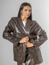 Blazer de mujer color marrón chocolate, confeccionado en ecocuero texturizado con acabado acharolado. Es forrado y presenta un corte estructurado con solapas y bolsillos frontales.