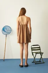 Vestido corto de corte recto y holgado, color camel, con breteles finos decorados con cuentas de colores en los extremos. Cuenta con bolsillos laterales.