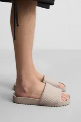 Chancla tipo pala monocolor negra, con suela de goma y tira ancha en el empeine con relieve acanalado.