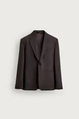 Blazer de corte regular fit confeccionado en tejido con lana, color marrón oscuro. Cuenta con cuello de solapas de muesca, manga larga con botones en los puños, bolsillos de vivo en el pecho y en la cadera, bolsillo interior y cierre frontal de un botón.