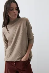 Polera de tejido de punto color gris oscuro, con cuello alto y diseño de rombos en relieve en el frente. Presenta un calce relajado con terminaciones en rib en cuello, puños y ruedo.