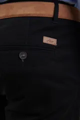 Pantalón de vestir verde oliva, de corte slim fit, sin pinzas, con bolsillos laterales y traseros. Se ajusta a la cintura con cinturón de cuero marrón.