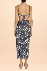 Pareo largo de diseño envolvente con nudo lateral, confeccionado en tejido fresco con estampado de motivos orgánicos en tonos verde y violeta sobre fondo blanco.