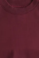Buzo deportivo de cuello redondo con hombros caídos, confeccionado en algodón de peso medio. Presenta puños y bajo en punto acanalado.