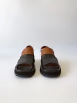 Sandalias de cuero color negro y marrón con textura tipo cocodrilo, con hebilla ajustable y suela track. Fabricadas en Uruguay.