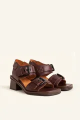 Sandalias de cuero negro con taco bloque de madera tallada, tiras con hebillas grandes y punta cuadrada.