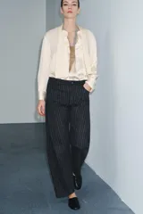 Pantalón de tiro medio con diseño balloon, confeccionado en tejido con patrón de rayas verticales. Presenta cintura con trabillas, cierre frontal con cremallera y botón, y cinco bolsillos.
