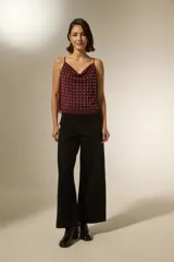 Musculosa negra de poliéster con cuello buche, breteles finos y apliques de tachas metálicas en toda la parte frontal.
