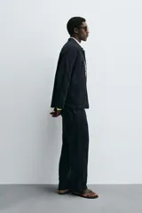 Sobrecamisa de algodón azul marino con textura jacquard de rayas verticales en relieve. Presenta cuello solapa, manga larga, cierre frontal de botones y dos bolsillos de parche grandes en la parte inferior delantera.