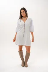 Vestido corto off-white con escote en V, de corte recto y holgado. Cuenta con mangas abullonadas tres cuartos confeccionadas en tejido broderie.