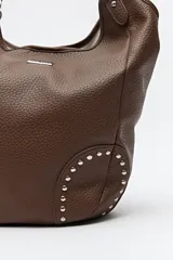 Bolso shopper marrón de símil cuero texturizado con asas cortas y detalles de tachas metálicas.