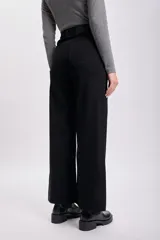 Pantalon de jean negro de corte ancho y tiro alto, con cierre frontal y bolsillos. Presenta un acabado deshilachado en el ruedo.