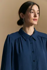Camisa de manga larga con caída fluida, diseño de silueta suelta, cuello clásico y cierre frontal con botones.