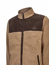 Campera polar con diseño combinado de sherpa color beige y paneles de cotelé color marrón oscuro en el canesú, cierre y bolsillos. Cuenta con cuello alto, cierre frontal completo y parche decorativo en el pecho.